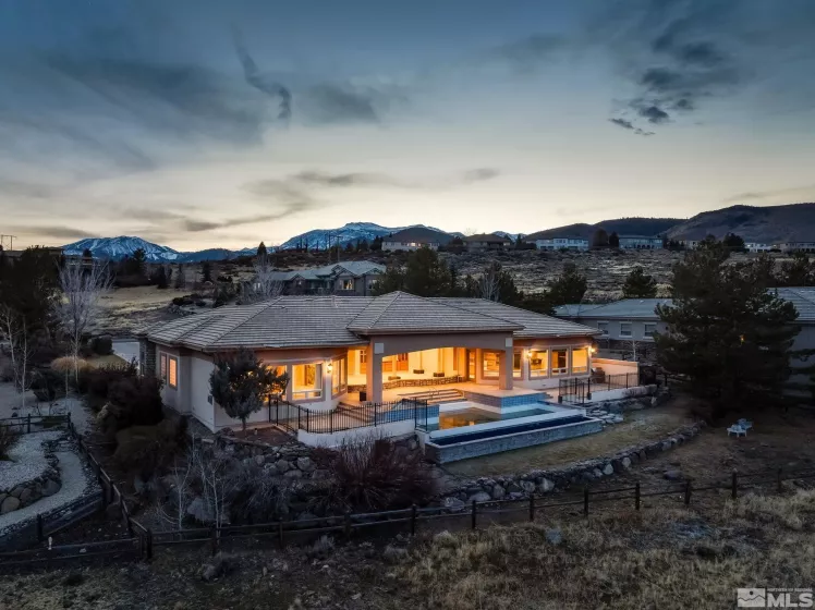 Twilight rear exterior with infinity-edge pool, best ArrowCreek golf-course and Reno skyline view.