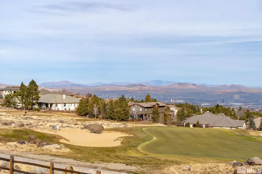Virtually staged dining/living with 20-ft glass wall framing uninterrupted golf-course panorama.