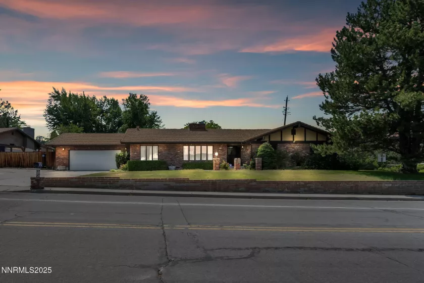 Beautiful curb appeal with a lush front lawn, mature trees, and timeless brick exterior on a spacious corner lot.