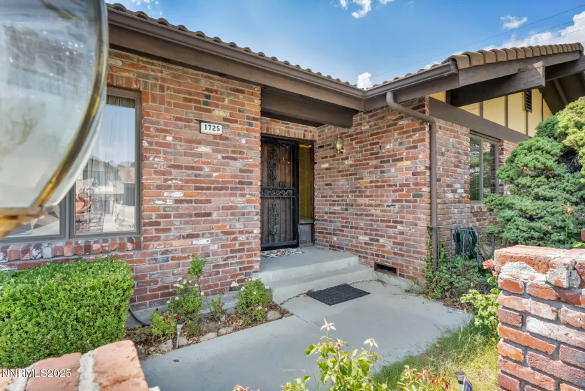 Charming front walkway leads through mature landscaping to the classic brick facade of this vintage home.