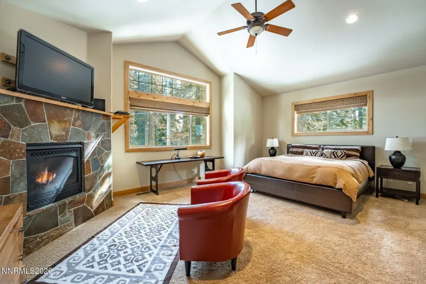 Primary suite with fireplace, large windows, and warm Tahoe lodge-inspired finishes.