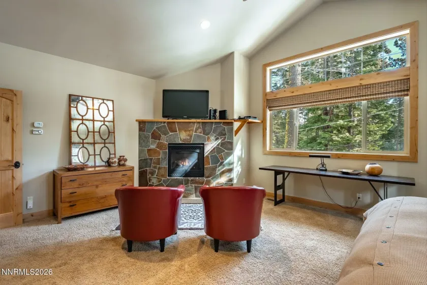 Spacious primary suite with fireplace, seating area, and peaceful forest views.