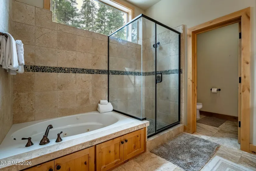 Primary spa-inspired bathroom featuring a soaking tub and oversized glass-enclosed shower.