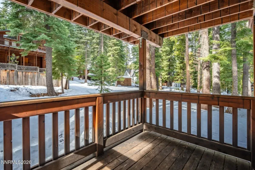 Covered deck surrounded by towering pines, offering year-round outdoor enjoyment.