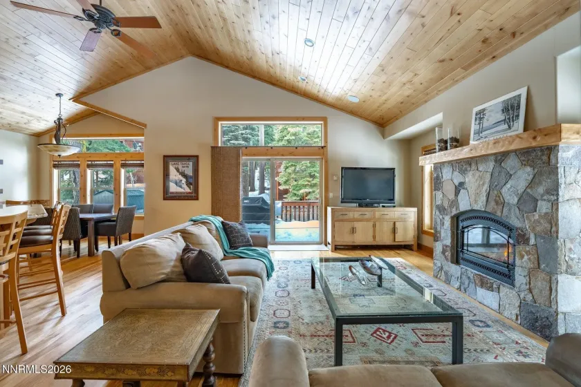 Light-filled great room with vaulted wood ceilings, stone fireplace, and open-concept living.
