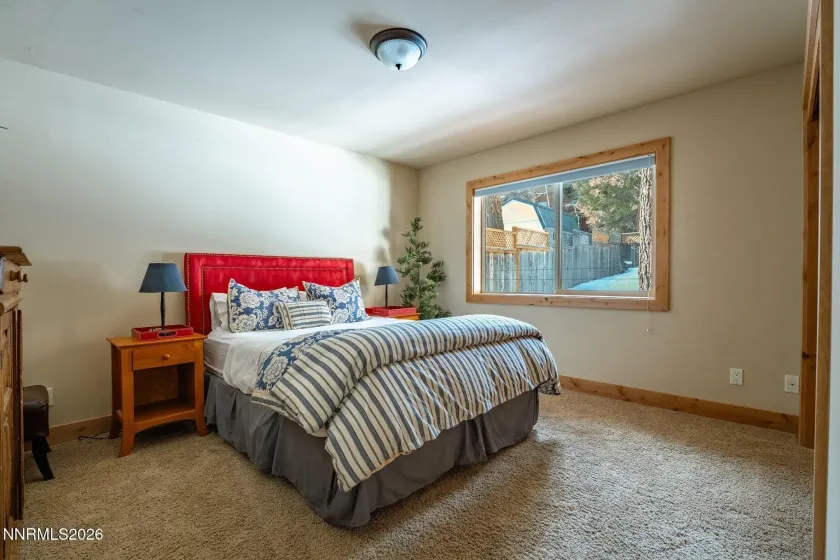 Comfortable guest bedroom with large window and peaceful forest setting.