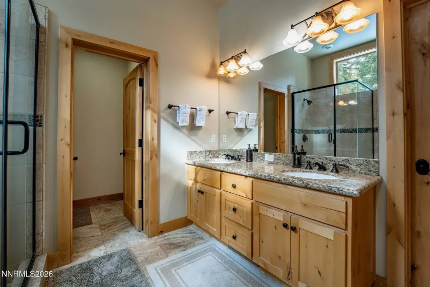 Well-appointed Primary bathroom with dual-sink vanity, granite counters, and ample storage.