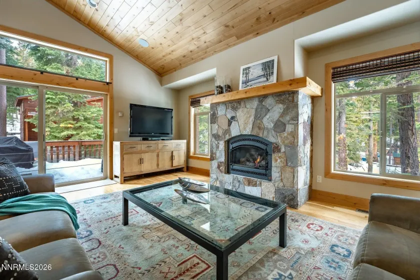 Inviting great room featuring a dramatic stone fireplace and forest views. 4