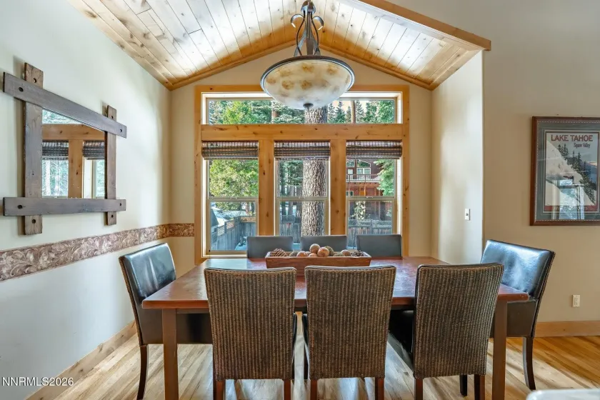 Dining area framed by soaring ceilings and French doors leading to outdoor living.