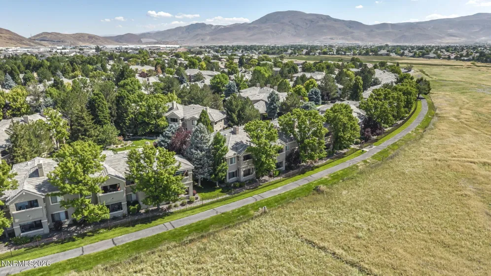 Aerial view showcasing the peaceful meadow and walking trail directly behind the condo, highlighting the home's private setting and beautiful natural surroundings.