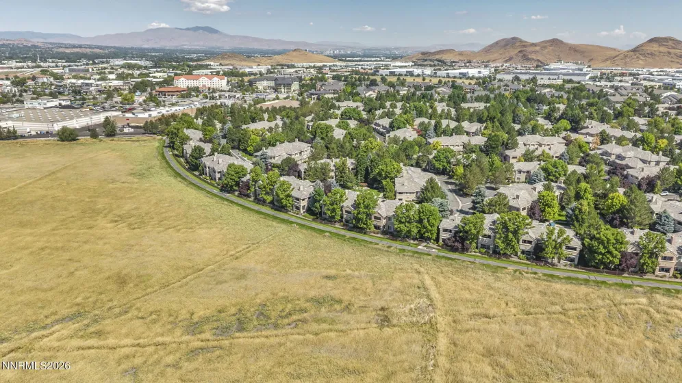 Aerial view showcasing the peaceful meadow and walking trail directly behind the condo, highlighting the home's private setting and beautiful natural surroundings.