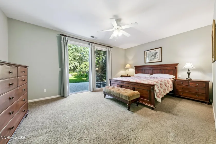 Spacious, light-filled primary bedroom with a sliding door providing direct access to the beautifully landscaped and serene backyard.