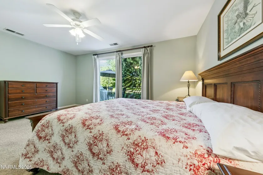 Spacious, light-filled primary bedroom with a sliding door providing direct access to the beautifully landscaped and serene backyard.