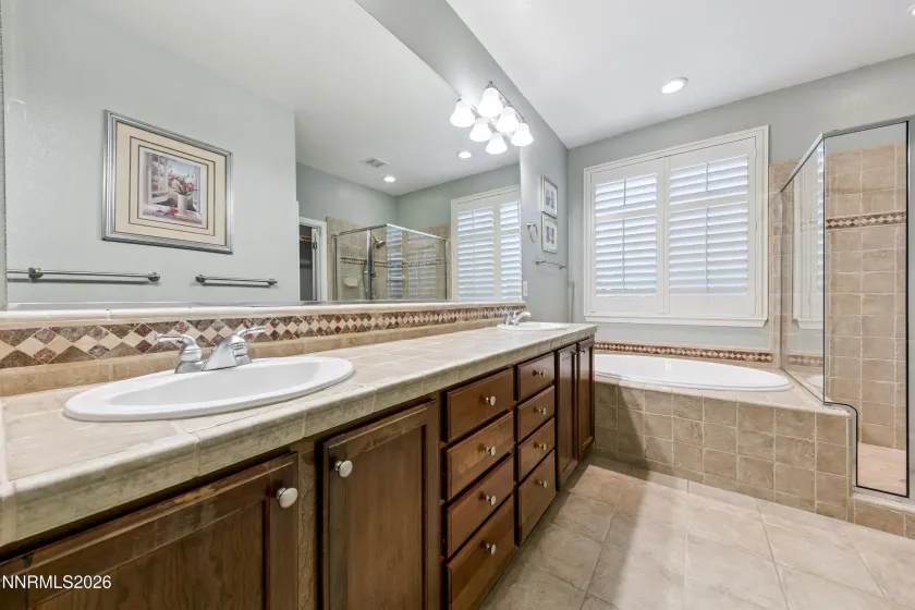 Spa-like primary bathroom featuring dual sinks, a relaxing jetted tub, and a separate shower for a comfortable, private retreat.