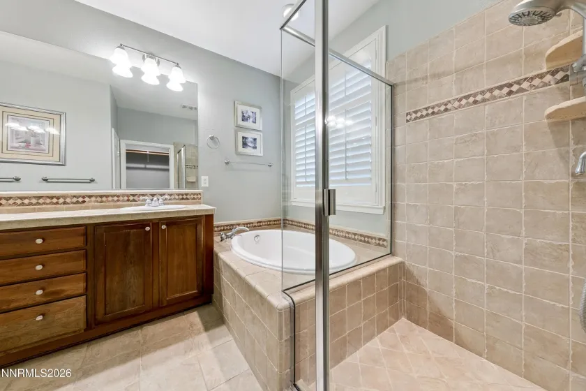 Spa-like primary bathroom featuring dual sinks, a relaxing jetted tub, and a separate shower for a comfortable, private retreat.