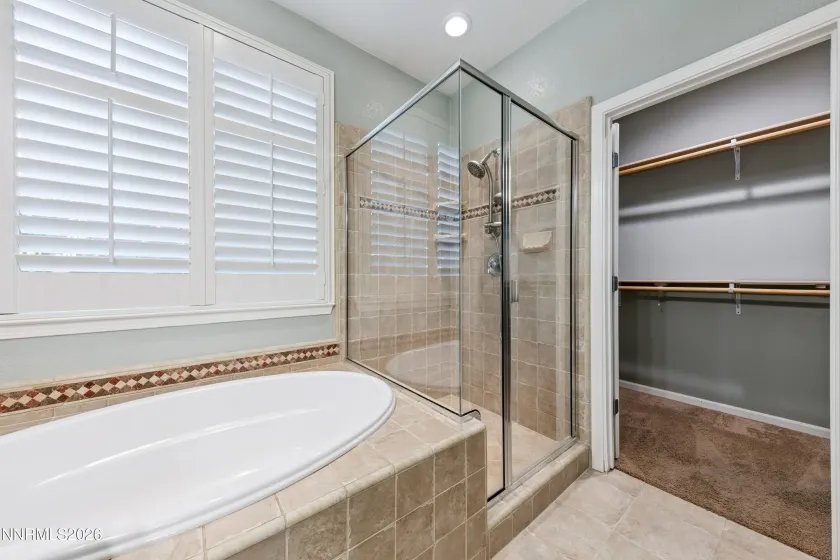 Spa-like primary bathroom featuring dual sinks, a relaxing jetted tub, and a separate shower for a comfortable, private retreat.