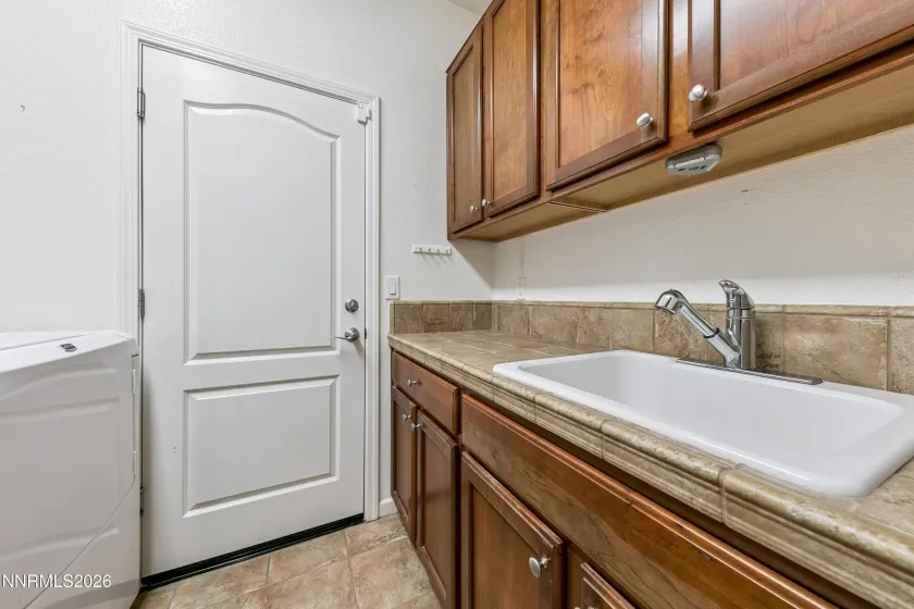 Dedicated laundry room with ample shelving, cabinetry, and a utility sink for added convenience and functionality.