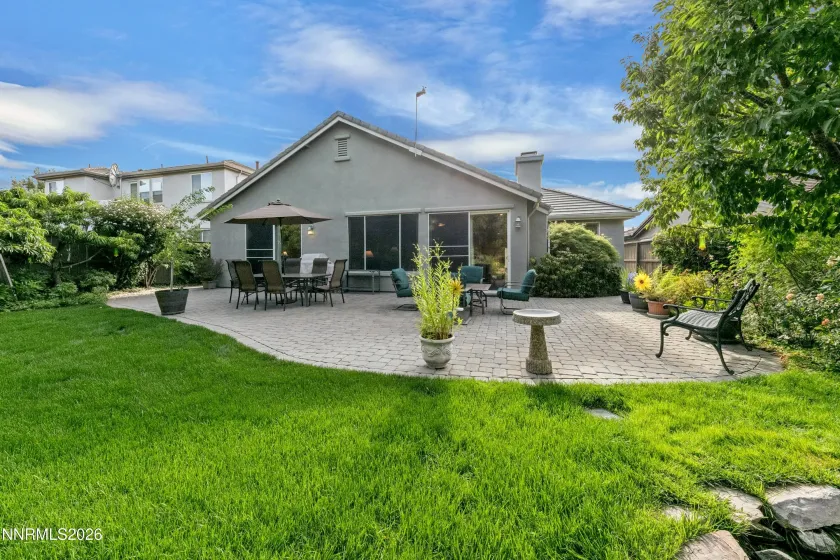 Gorgeous, lush backyard featuring a tranquil water feature and paver patio, creating a private and serene retreat ideal for outdoor entertaining and relaxation.