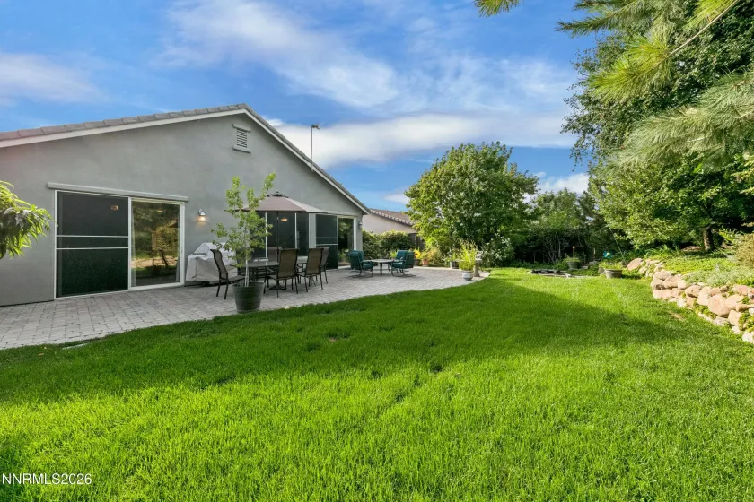 Gorgeous, lush backyard featuring a tranquil water feature and paver patio, creating a private and serene retreat ideal for outdoor entertaining and relaxation.