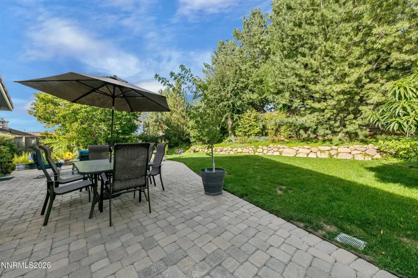 Gorgeous, lush backyard featuring a tranquil water feature and paver patio, creating a private and serene retreat ideal for outdoor entertaining and relaxation.