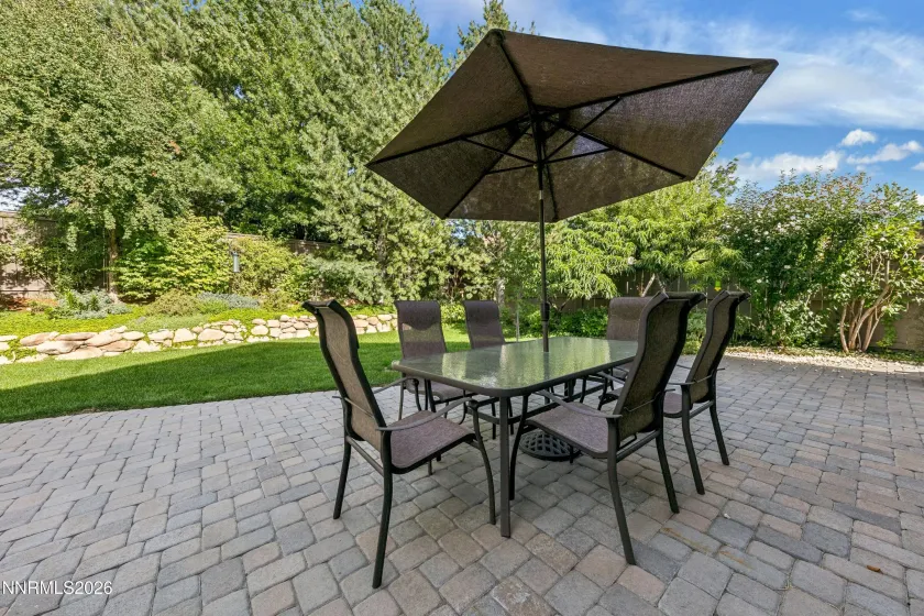 Gorgeous, lush backyard featuring a tranquil water feature and paver patio, creating a private and serene retreat ideal for outdoor entertaining and relaxation.