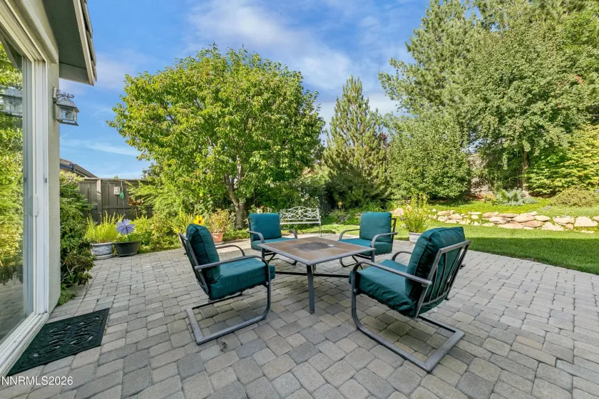 Gorgeous, lush backyard featuring a tranquil water feature and paver patio, creating a private and serene retreat ideal for outdoor entertaining and relaxation.