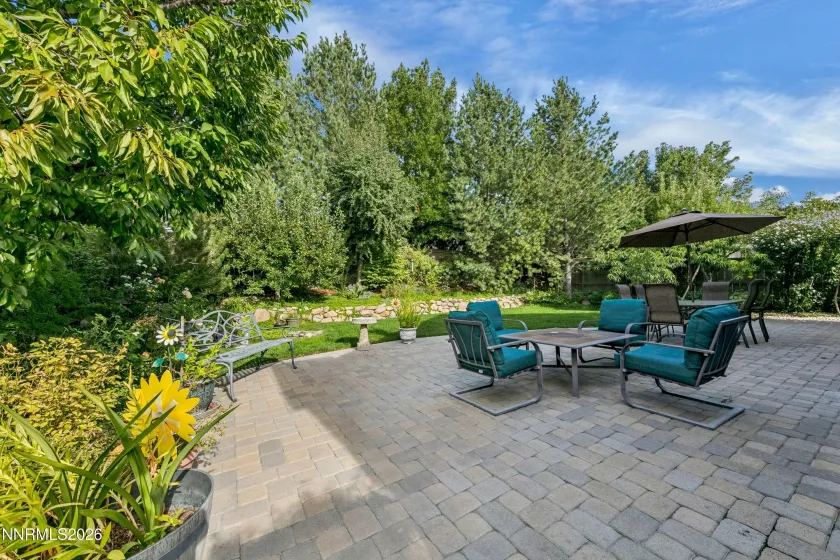 Gorgeous, lush backyard featuring a tranquil water feature and paver patio, creating a private and serene retreat ideal for outdoor entertaining and relaxation.
