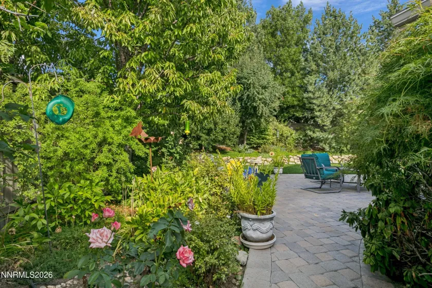 Gorgeous, lush backyard featuring a tranquil water feature and paver patio, creating a private and serene retreat ideal for outdoor entertaining and relaxation.