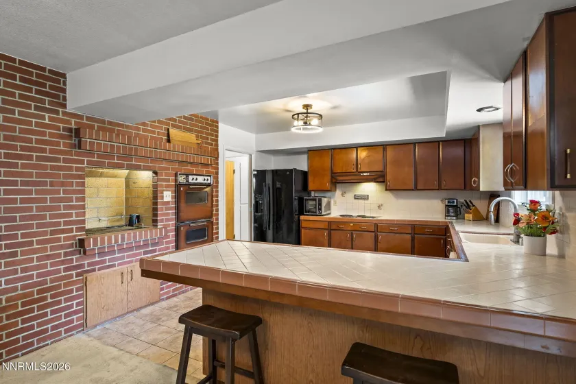 Shot of the breakfast bar, kitchen, indoor rotisserie & vintage double ovens.